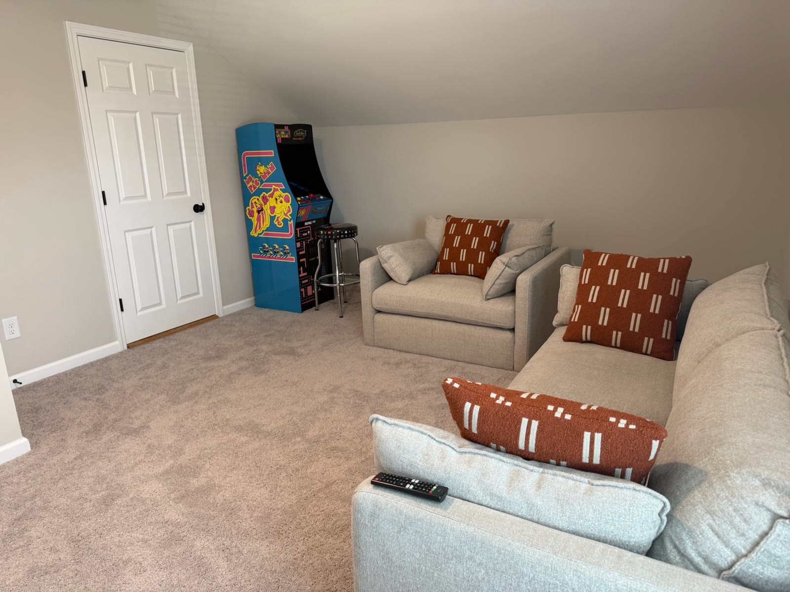 Furnished game room with arcade cabinet and seating