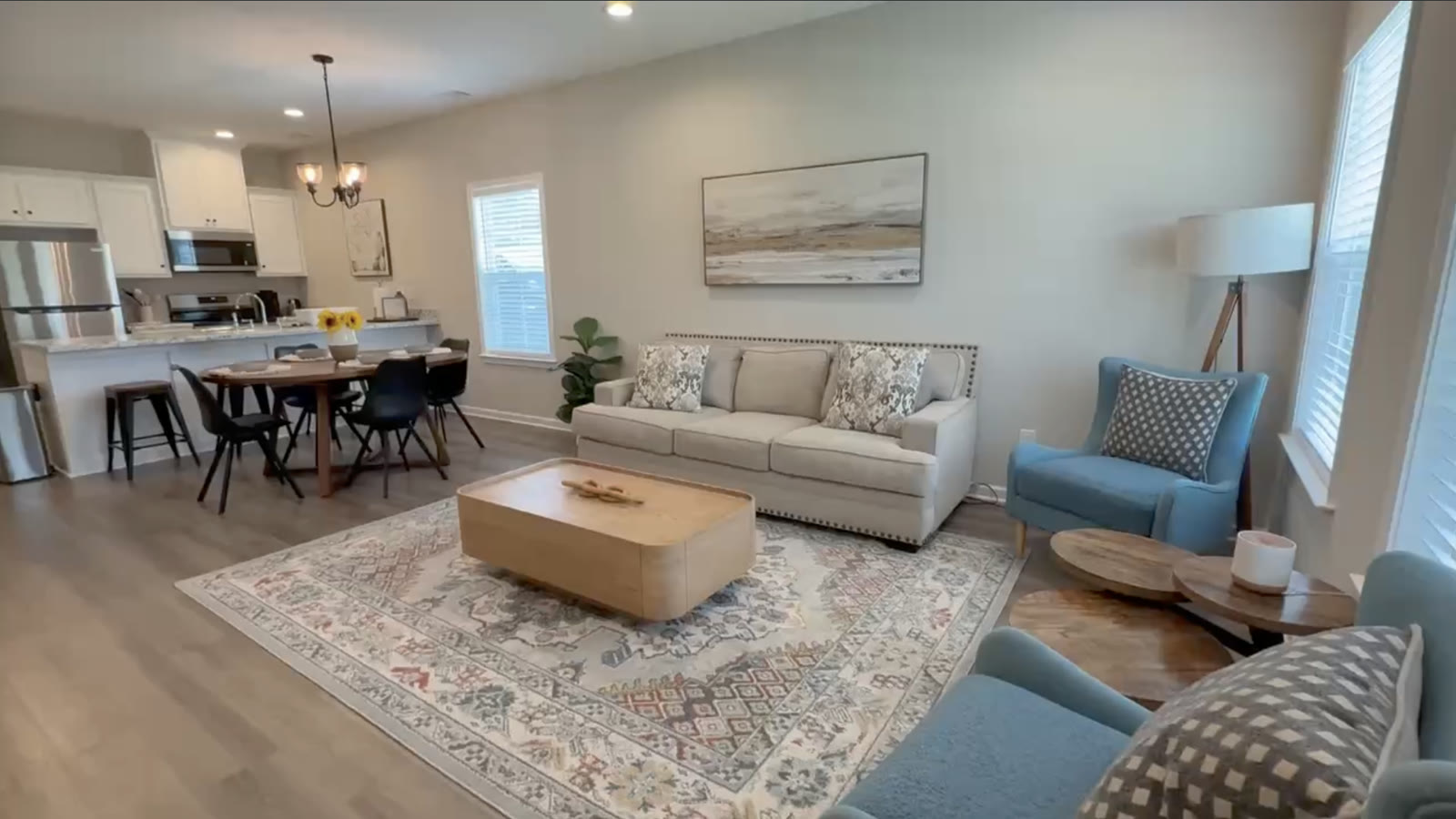 Wide view of the furnished living, dining, and kitchen area